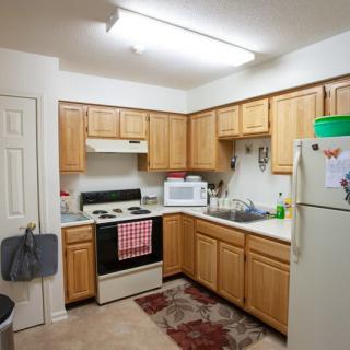 A cozy kitchen with wooden cabinets, white appliances, and a tiled floor.