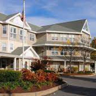 A residential building surrounded by landscaped gardens and a flagpole.