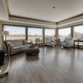 A modern living room with large windows, sleek furniture, and a hardwood floor.