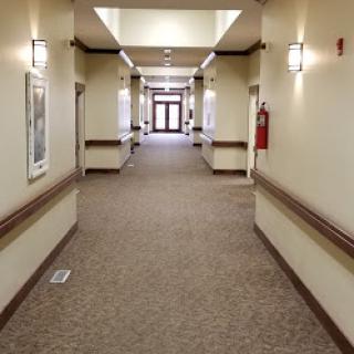 A spacious and well-lit hallway with carpeted flooring, leading to doors at the end.