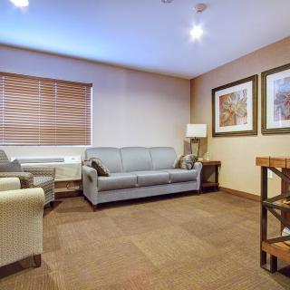 A cozy living room with a sofa, chairs, and wall artwork.