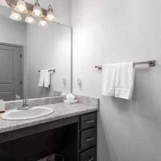 A modern bathroom with a sink, mirror, and towel on a rack.