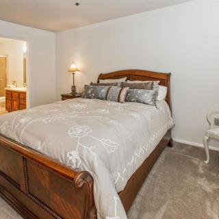 A cozy bedroom featuring a large wooden bed with plush bedding and an elegant lamp on the nightstand.