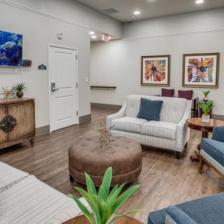 A cozy and elegantly designed living room featuring comfortable sofas, a central coffee table, wall artwork, and decorative plants.