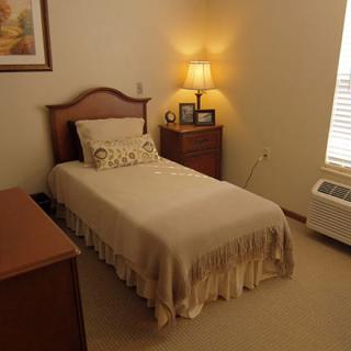 A cozy bedroom with a single bed and warm lighting.