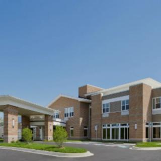 A modern hospital building with a clear blue sky background.