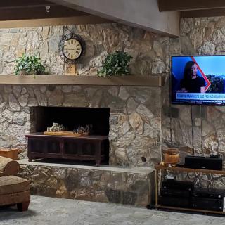 A cozy living room with a stone fireplace and a mounted television.