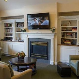 A cozy living room with a fireplace, television, and built-in shelves.