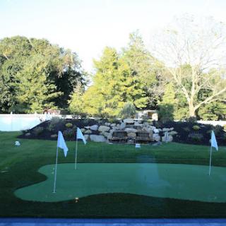 A serene putting green surrounded by lush greenery.