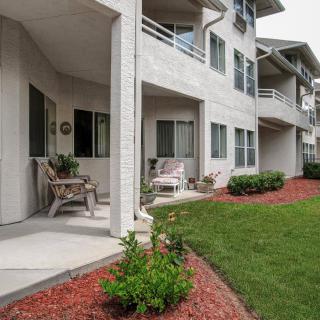 A view of an apartment building with patios and balconies overlooking a landscaped area with neatly trimmed grass.