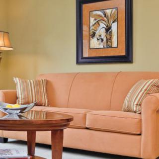 A cozy living room featuring an orange sofa with striped pillows, a wooden coffee table, and wall art.