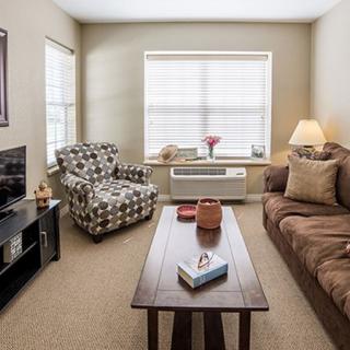 A cozy living room with a sofa, armchair, coffee table, and television.