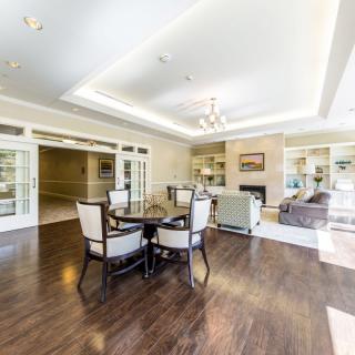 A spacious and modern living room with a dining area, featuring hardwood floors and elegant furniture.