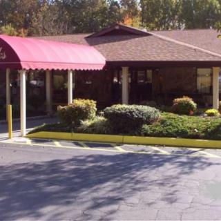 A building entrance with a red awning and surrounding landscaping.