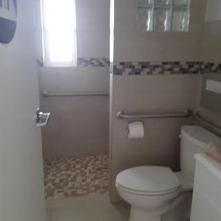 A bathroom with a toilet, sink, and a tiled shower area.