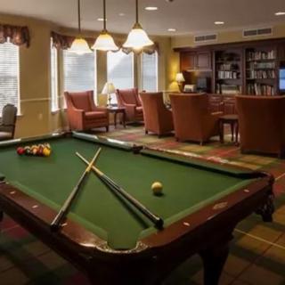 A cozy recreation room featuring a pool table, comfortable seating, and bookshelves.