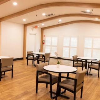 A modern dining area with tables and chairs arranged neatly on a wooden floor.