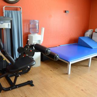 A physical therapy room equipped with exercise machines and a treatment table.