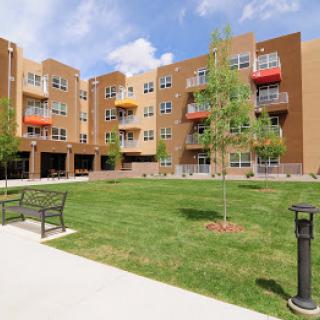 A modern apartment complex with a well-maintained lawn and outdoor seating areas.