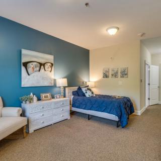 A modern bedroom featuring a single bed with a blue accent wall and tasteful decor.