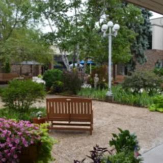 A peaceful garden with a wooden bench, surrounded by lush greenery and colorful flowers.