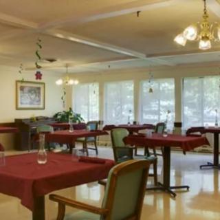 An empty dining room with red tablecloths and neatly arranged furniture.