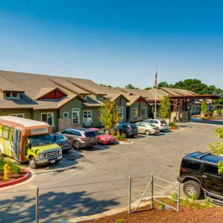 A row of buildings with a parking lot filled with cars under a clear blue sky.