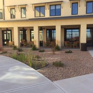 A view of a building with outdoor seating and landscaped surroundings.