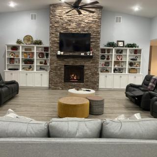 A modern living room with a stone fireplace, large television, and comfortable seating area.
