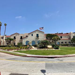 A picturesque building surrounded by lush greenery and palm trees under a clear blue sky.