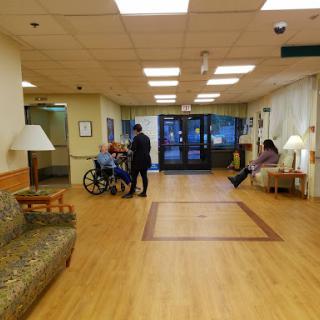 A spacious waiting area in a healthcare facility, featuring a wheelchair and individuals engaging with each other.
