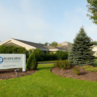 A well-manicured exterior view of a healthcare facility with neatly trimmed gardens and a prominent sign.