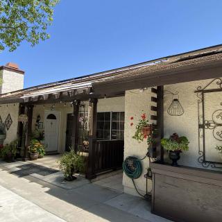 A charming house with a porch and plants under a clear blue sky.
