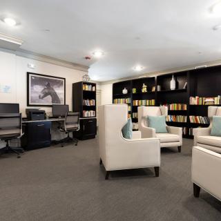 A modern library interior with comfortable seating, bookshelves, and computer workstations.