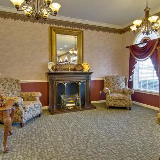 A classic living room with a fireplace, adorned with chandeliers and armchairs.