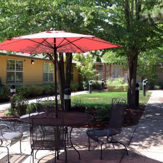 A sunny patio with outdoor seating and a red umbrella.