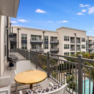 A modern balcony overlooking a swimming pool and adjacent apartment complex.