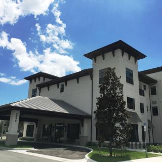 A modern hotel building with a backdrop of blue sky and clouds.