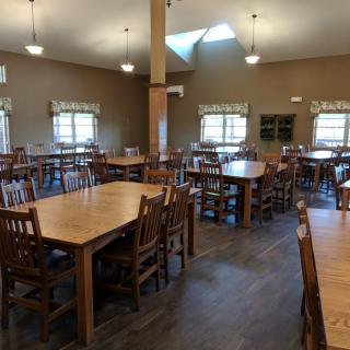 An empty dining hall with wooden tables and chairs arranged neatly.