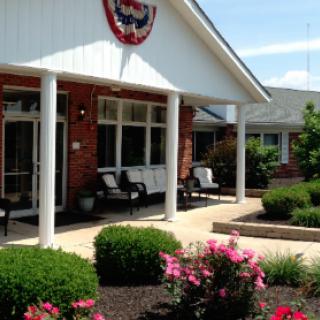 A charming residential building with a welcoming front porch and vibrant flowers in the landscaping.