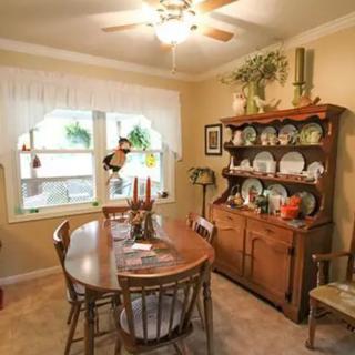 A cozy dining room with a wooden table and chairs, complemented by a hutch displaying dishes and decor.