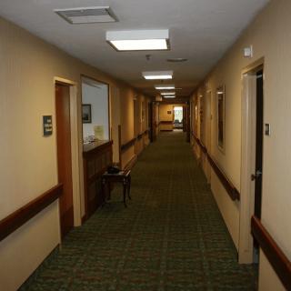 A well-lit corridor with carpet flooring and multiple doors.