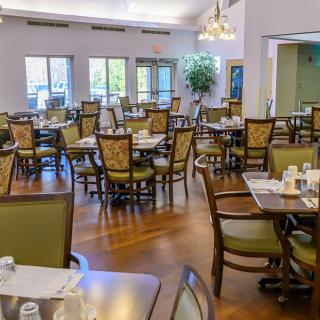 An empty dining room with neatly arranged tables and chairs, illuminated by natural light.