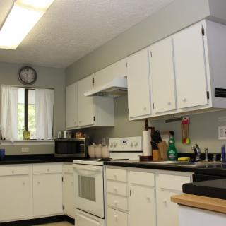 Modern kitchen with white cabinets and various appliances.
