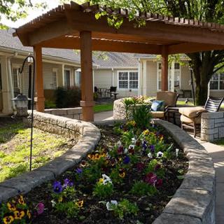 A beautiful garden with vibrant flowers and a shaded seating area under a pergola.