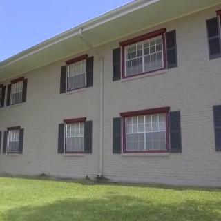 A residential building with multiple windows and a grassy lawn.