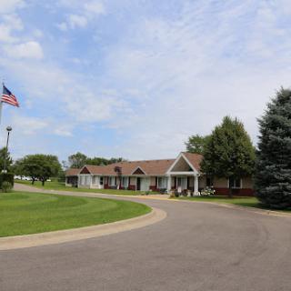 A peaceful residential building with an American flag, surrounded by greenery and a winding road.