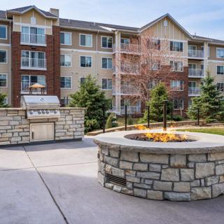 A modern apartment building with a landscaped outdoor area featuring a stone fire pit.
