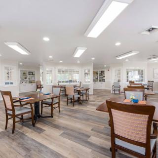 A spacious, well-lit interior with wooden chairs and tables arranged neatly on a polished floor.