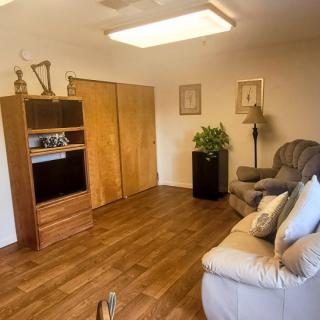 Cozy living room with a sofa, television, and wooden flooring.